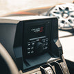 Close-up of a vehicle's dashboard showcasing an RPM Series All-Weather Audio Player/Receiver - CMR3 with its logo. It features Bluetooth streaming, control buttons, and a central knob. A speaker is partially visible to the right, blurred under sunlight illuminating this audio system.