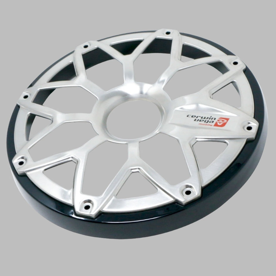 The RPM Stroker 6.5” Flush Mount Speaker Grill has a silver cover with an interlocking diamond pattern, bolt holes around the edge, and a small red logo with text on one segment against a plain gray background.